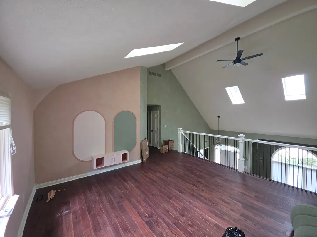 The play area with peach and sage plaster, arched boards on the far wall, and a railing to the stairs