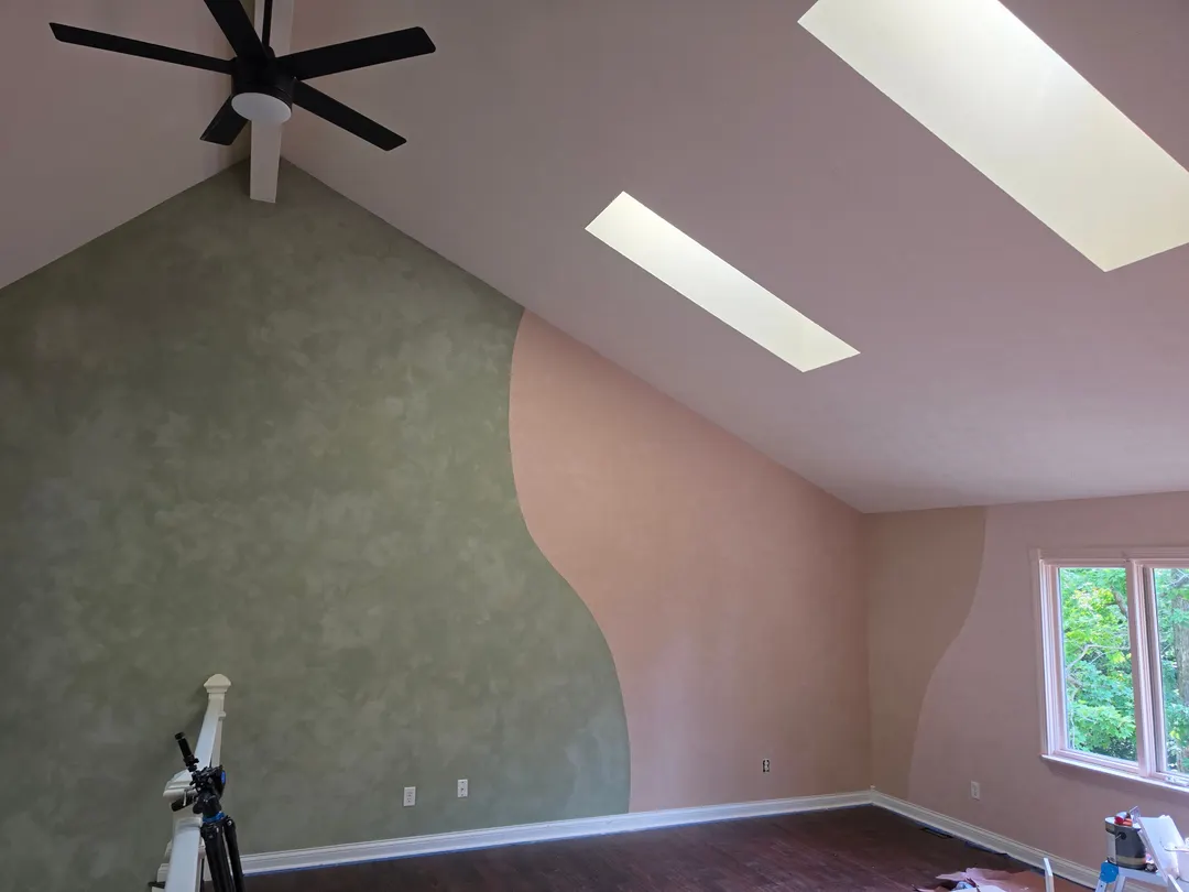 Sage and peach lime plaster walls meeting in a soft curve under a sloped ceiling, in a Geist play area
