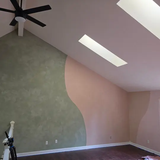 Sage and peach lime plaster walls meeting in a soft curve under a sloped ceiling, in a Geist play area