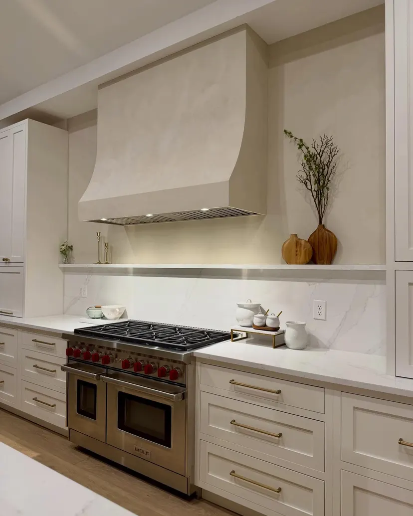 The cream plaster hood seen from the side, its curve over the range and the shelf below it