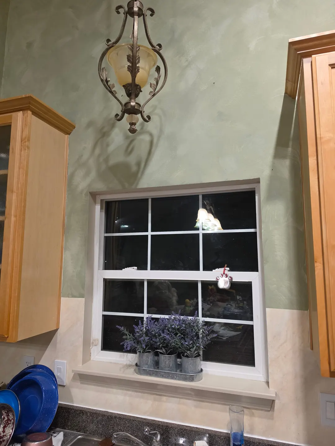 Gray-green Cypress Ink limewash on a kitchen wall around a window, above a polished cream marble backsplash, in a Zionsville home